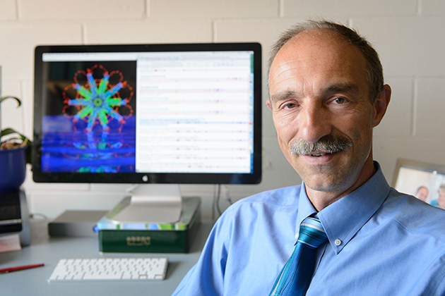 Peter Burkhard, professor of molecular and cell biology, with an image of the protein nanoparticle he designed. (Peter Morenus/UConn Photo)